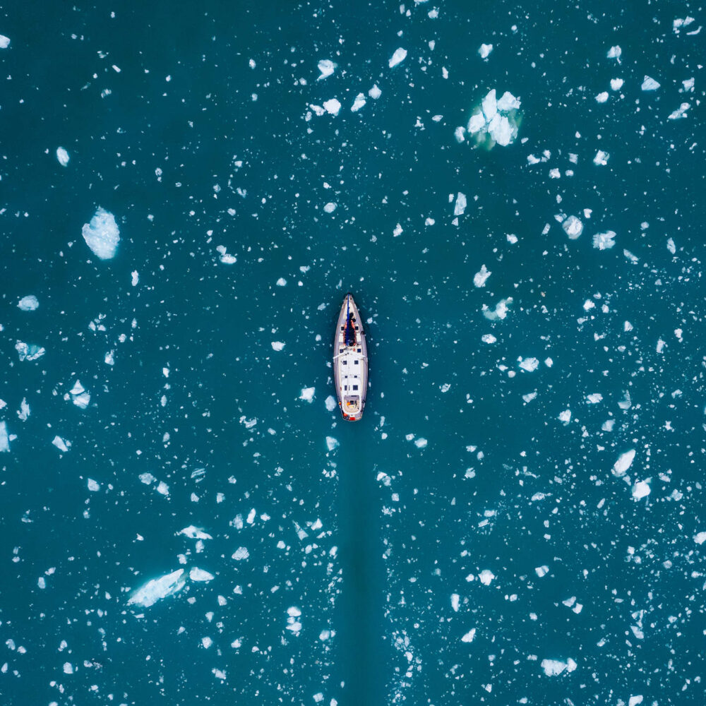 Top down view of sail boat sailing through ice in the arctic