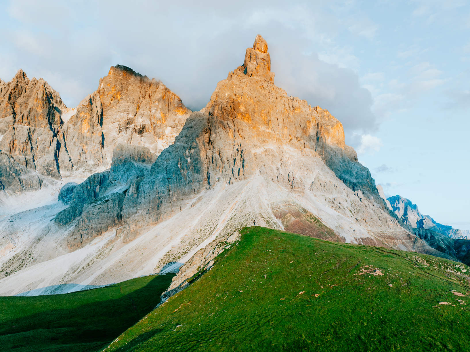 Hiking in front of a tall mountain at sunset in the dolomites